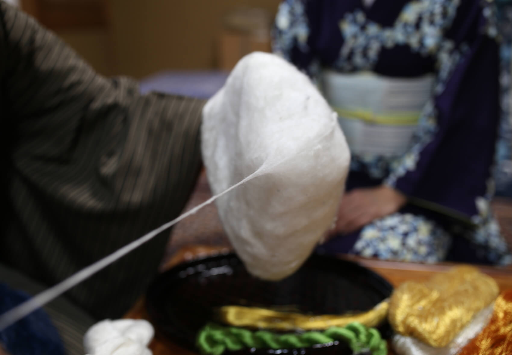 ねん金糸を作るために、まずは蚕から手紡ぎの真綿を撚り上げます。
